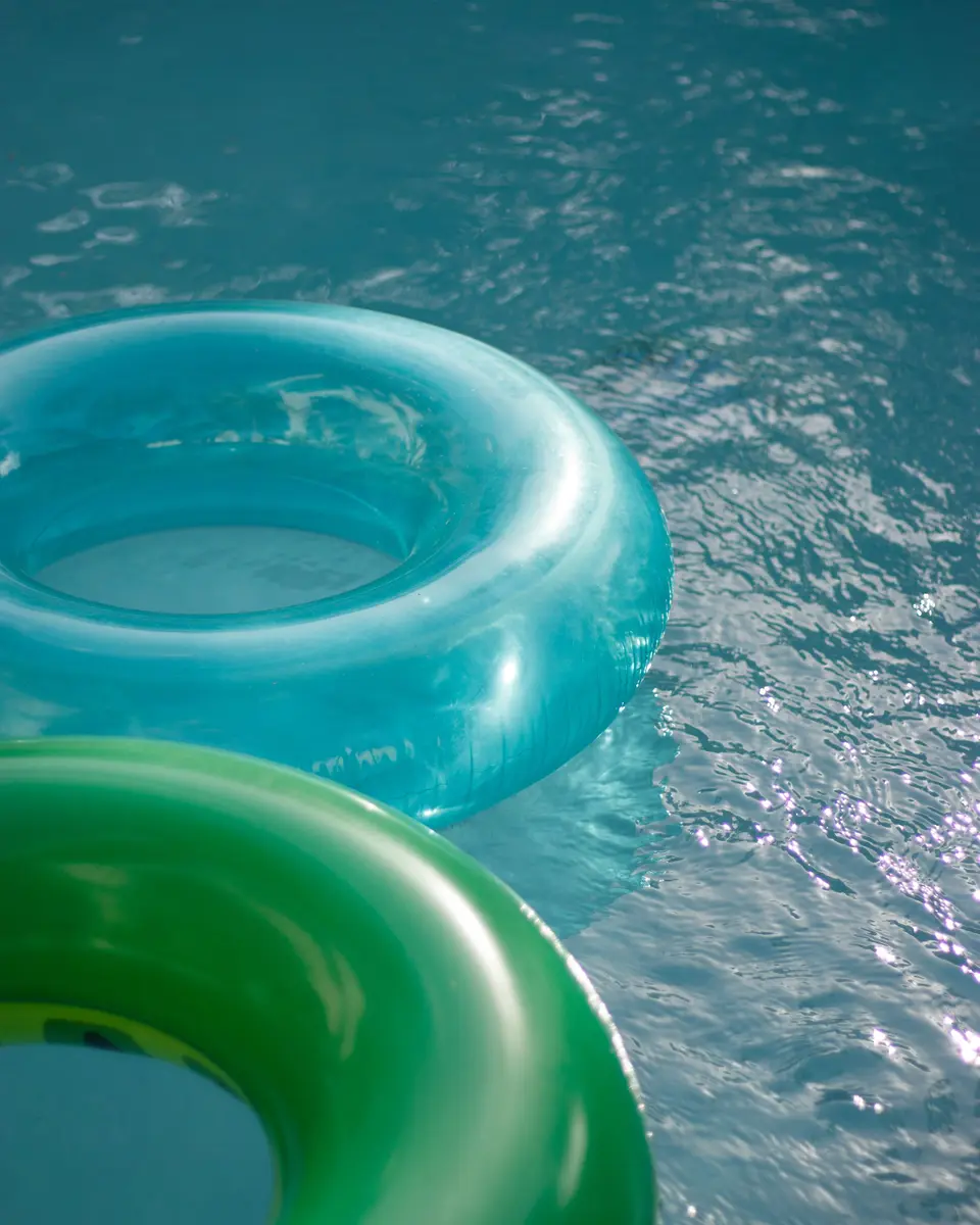 Blaue und grüne aufblasbare Ringe auf leuchtendem Wasser
